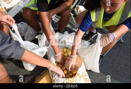 Orlando, Usa. 25.. Juni 2022. Freiwillige legen Kartoffeln in kleine Tüten bei einer Lebensmittelverteilung für Bedürftige, die von der Second Harvest Food Bank of Central Florida und Orange County in der St. John Vianney Church in Orlando, Florida gesponsert wird. Hohe Lebensmittel- und Gaspreise drücken die arbeitenden Familien unter Druck und schicken einige zum ersten Mal in Lebensmittelvorratskammern, aber die Anbieter kämpfen mit den Inflationskosten, da die Nachfrage steigt. (Foto von Paul Hennessy/SOPA Images/Sipa USA) Quelle: SIPA USA/Alamy Live News Stockfoto