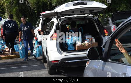 Orlando, Usa. 25.. Juni 2022. Freiwillige laden Lebensmittelsäcke in Autos bei einer Lebensmittelverteilungsveranstaltung für Bedürftige, die von der Second Harvest Food Bank of Central Florida und Orange County in der St. John Vianney Church in Orlando, Florida, gesponsert wird. Hohe Lebensmittel- und Gaspreise drücken die arbeitenden Familien unter Druck und schicken einige zum ersten Mal in Lebensmittelvorratskammern, aber die Anbieter kämpfen mit den Inflationskosten, da die Nachfrage steigt. (Foto von Paul Hennessy/SOPA Images/Sipa USA) Quelle: SIPA USA/Alamy Live News Stockfoto