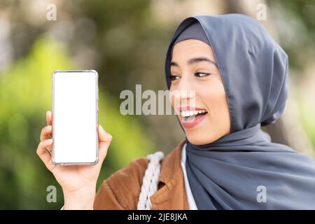 Freundliche muslimische Frau, die den Bildschirm des Handys zeigt Stockfoto
