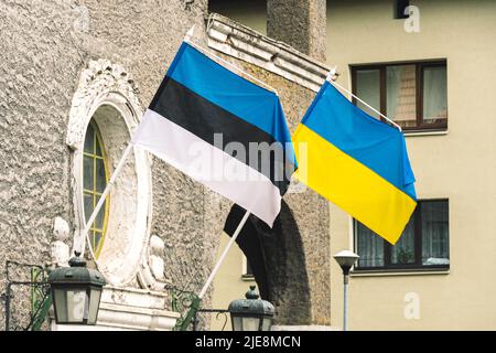 Die Flagge Estlands und der Ukraine winkt zusammen an der Wand eines Gebäudes Stockfoto