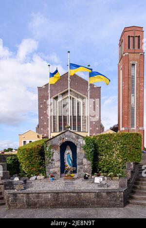 Drei ukrainische Flaggen fliegen auf Fahnenmasten vor der Kirche St. Peter und St. Paul, Portlaoise, County Laois, Republik Irland. Stockfoto