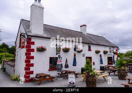 Hübscher, traditioneller irischer Pub im ländlichen Raum mit Picknicktischen im Freien. Stockfoto