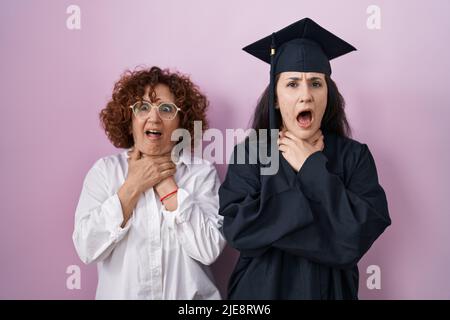 Hispanische Mutter und Tochter tragen Abschlusskappe und Zeremonie Robe schreiend und ersticken, weil schmerzhafte Erwürgung. Gesundheitsproblem. Erstickungsrate und Stockfoto