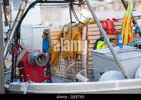 Die gelbe wasserdichte Schutzkleidung von Fisherman wird auf einem kommerziellen Fischerboot in Katalonien, Spanien, zum Trocknen zurückgelassen Stockfoto