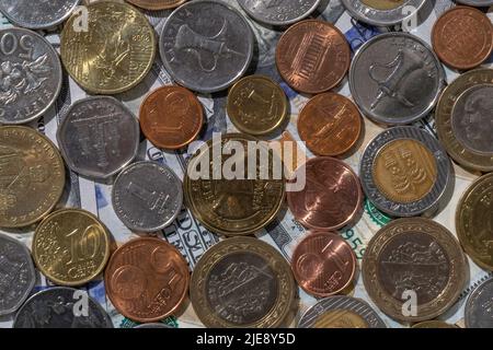 Geldwechsel: Verschiedene Länder Münzen liegen auf hundert Dollar-Banknoten Stockfoto