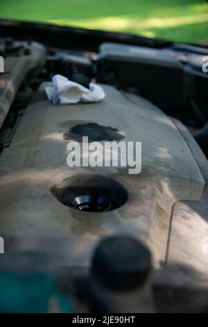 Abgeschraubter Motoröldeckel auf verschmutzter Motorkunststoff-Dekorabdeckung. Stockfoto