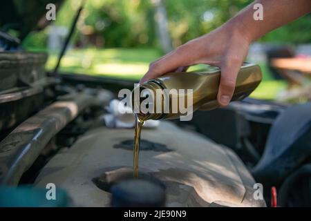 Nahaufnahme Hand Mechaniker Reparatur wechseln das Öl. Kfz-Mechaniker gießt frisches Öl in die Motorreparatur an der Tankstelle. Stockfoto