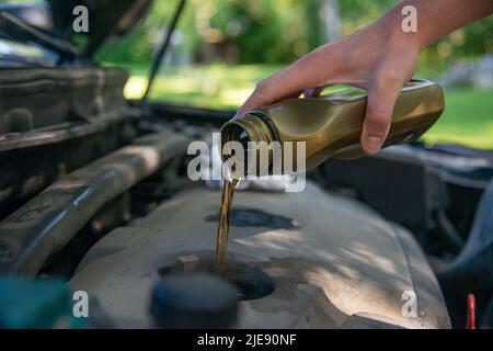 Nahaufnahme Hand Mechaniker Reparatur wechseln das Öl. Kfz-Mechaniker gießt frisches Öl in die Motorreparatur an der Tankstelle. Stockfoto