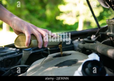 Nahaufnahme Hand Mechaniker Reparatur wechseln das Öl. Kfz-Mechaniker gießt frisches Öl in die Motorreparatur an der Tankstelle. Stockfoto