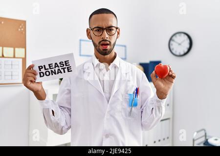 afroamerikanischer Arzt Mann, der Organe unterstützt, spendet ahnungslose und verwirrte Ausdrucksweise. Zweifel Konzept. Stockfoto