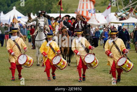 Eine Person, die die Rolle von König Charles II. Spielt, winkt während eines Pageants aus der Zeit der Restaurierung während des Chalke Valley History Festivals in Broad Chalke, in der Nähe von Salisbury, Wiltshire, zur Krone. Bilddatum: Sonntag, 26. Juni 2022. Stockfoto