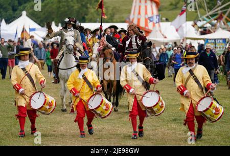 Eine Person, die die Rolle von König Charles II. Spielt, winkt während eines Pageants aus der Zeit der Restaurierung während des Chalke Valley History Festivals in Broad Chalke, in der Nähe von Salisbury, Wiltshire, zur Krone. Bilddatum: Sonntag, 26. Juni 2022. Stockfoto