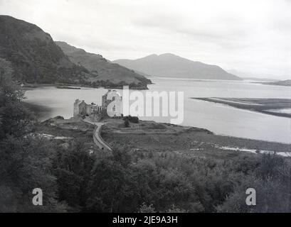 1950s, historische Ansicht aus dieser Zeit des Eilean Donan Schlosses und der umliegenden Landschaft mit Hochland und Lochs, schottisches Hochland, Schottland, Großbritannien. Das Schloss wurde erstmals im 13.. Jahrhundert erbaut und 1719 zerstört, als eine spanische Flotte eintraf, um den Jakobitenaufstand zu unterstützen. Es wurde zwischen 1919 und 1932 von LT Co. John MacRae-Gilstrap, ein Verwandter des Clan MacRae, ursprüngliche Konstables der MacKenzies von Kintail, Besitzer des Schlosses und der umliegenden Länder, umgebaut. Es wurde 1955 der Öffentlichkeit zugänglich gemacht. Stockfoto