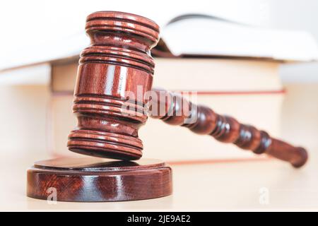 Öffnen Sie ein Gesetzbuch mit einem hölzernen Richter-Gavel auf dem Tisch in einem Gerichtssaal oder Strafverfolgungsbüro Stockfoto
