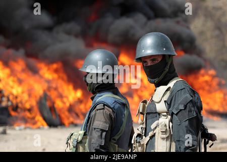 Sanaa, Jemen. 26.. Juni 2022. Jemenitische Soldaten stehen Wache, während Flammen und Rauch von einem brennenden Haufen beschlagnahmter Drogen während einer Zerstörungszeremonie aufsteigen, die anlässlich des Internationalen Tages gegen Drogenmissbrauch und illegalen Handel organisiert wurde. Die von Huthi betriebenen Sicherheitsdienste haben mehr als 40 Tonnen beschlagnahmter Betäubungsmittel verbrannt und zerstört. Quelle: Hani Al-ANSI/dpa/Alamy Live News Stockfoto