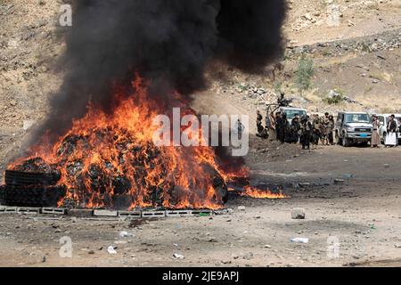 Sanaa, Jemen. 26.. Juni 2022. Jemenitische Soldaten stehen Wache, während Flammen und Rauch von einem brennenden Haufen beschlagnahmter Drogen während einer Zerstörungszeremonie aufsteigen, die anlässlich des Internationalen Tages gegen Drogenmissbrauch und illegalen Handel organisiert wurde. Die von Huthi betriebenen Sicherheitsdienste haben mehr als 40 Tonnen beschlagnahmter Betäubungsmittel verbrannt und zerstört. Quelle: Hani Al-ANSI/dpa/Alamy Live News Stockfoto