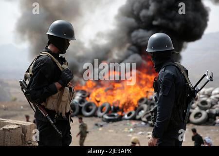 Sanaa, Jemen. 26.. Juni 2022. Jemenitische Soldaten stehen Wache, während Flammen und Rauch von einem brennenden Haufen beschlagnahmter Drogen während einer Zerstörungszeremonie aufsteigen, die anlässlich des Internationalen Tages gegen Drogenmissbrauch und illegalen Handel organisiert wurde. Die von Huthi betriebenen Sicherheitsdienste haben mehr als 40 Tonnen beschlagnahmter Betäubungsmittel verbrannt und zerstört. Quelle: Hani Al-ANSI/dpa/Alamy Live News Stockfoto