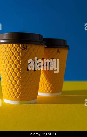Ukraine, Kiew - 17. Februar 2021: Gelbes Glas Kaffee von McDonald's. Papierglas Getränk McCafe. Kaffeetasse auf Tisch mit Schatten. Speisekarte im Fastfood-Restaurant. Stockfoto