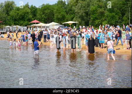 Norderstedt, Deutschland. 26.. Juni 2022. Zahlreiche Getaufte stehen mit Pastoren und ihren Familien am Ufer des Stadtparksee. Eine Massentaufe mit 57 Teilnehmern und rund 500 Gästen wurde von sieben Kirchengemeinden am und im Stadtparksee in Norderstedt bei Hamburg gefeiert. Quelle: Jonas Walzberg/dpa/Alamy Live News Stockfoto