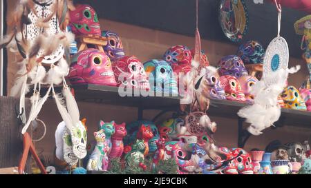 Mexikanische Souvenirs am Marktstand, bunt bemalte Totenköpfe und Traumfänger. Farbenfrohe, lebendige ethnische Ornamente, Basar oder Marktplatz. Keramik gefertigt Tod Symbol zum Verkauf auf der Theke. Tag der Toten. Stockfoto