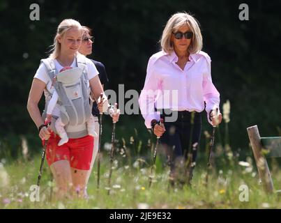 Elmau, Deutschland. 26.. Juni 2022. Miriam Neureuther, ehemalige Biathletin (l-r) mit Kind in Babytrage, Amelie Derbaudrenghien (versteckt hinter), Partnerin von EU-Ratspräsident Charles Michel, und Brigitte Macron, Ehefrau des französischen Präsidenten Emmanuel Macron, auf einer gemeinsamen Nordic-Walking-Tour. Am ersten Tag des Gipfels werden die globale Wirtschaftslage, der Klimaschutz sowie die Außen- und Sicherheitspolitik mit den Sanktionen gegen Russland diskutiert. Quelle: Karl-Josef Hildenbrand/dpa/Alamy Live News Stockfoto