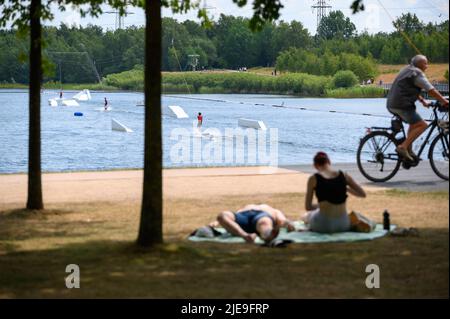 Norderstedt, Deutschland. 26.. Juni 2022. Mehrere Wasserskifahrer sind auf dem Stadtparksee unterwegs, während Tagesausflügler die Sonne am Ufer genießen. Quelle: Jonas Walzberg/dpa/Alamy Live News Stockfoto