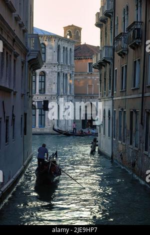 Venedig, Italien - 04. September 2018: Wasserkanal, Italienischer Mann mit der Gondel rudert auf einem schmalen Kanal, der Touristen in der Nachmittagsumgebung herumträgt Stockfoto