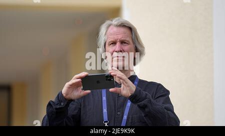 Elmau, Deutschland. 26.. Juni 2022. Dietmar Müller-Elmau, Eigentümer und Hotelmanager von Schloss Elmau, hält während des Gipfeltreffens G7 sein Smartphone. Deutschland veranstaltet vom 26. Bis 28. Juni G7 2022 den Gipfel der wirtschaftlich starken Demokratien auf Schloss Elmau. Am ersten Tag des Gipfels werden die globale Wirtschaftslage, der Klimaschutz sowie die Außen- und Sicherheitspolitik mit Sanktionen gegen Russland diskutiert. Quelle: Michael Kappeler/dpa/Alamy Live News Stockfoto