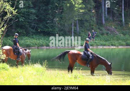 Elmau, Deutschland. 26.. Juni 2022. Olizisten der Reiterstaffel bewässern ihre Pferde am Ufer des Ferchensee nach einer gemeinsamen Nordic-Walking-Tour durch die Partner der G7 Teilnehmer. Deutschland wird vom 26. Bis 28. Juni G7 2022 Gastgeber des Gipfels der wirtschaftlich starken Demokratien sein. Quelle: Karl-Josef Hildenbrand/dpa/Alamy Live News Stockfoto