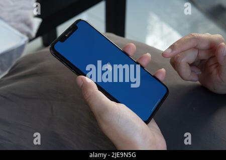 CHIANG MAI, THAILAND - 12. FEB 2022: Frau mit Apple iPhone X und Twitter-Anwendung auf dem Bildschirm am Bahnhof.Twitter-Anwendung Stockfoto