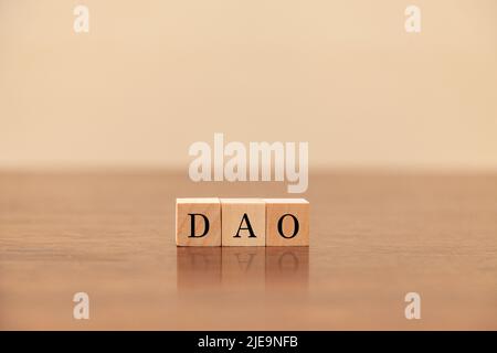 DAO-Zeichen. Dezentrale autonome Organisation. Geschrieben auf drei Holzblöcken. Schwarze Buchstaben. Holztisch Hintergrund. Stockfoto
