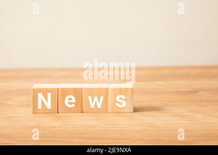 Nachrichten Zeichen. nachrichten. Was ist neu? Geschrieben auf vier Holzblöcken, die auf einem Holztisch stehen. Weiße Buchstaben. Stockfoto