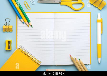 Draufsicht auf leeren Notizblock geöffnet und Schulbedarf mit Platz für Text auf blauem Hintergrund. Zurück zum Schulkonzept Stockfoto