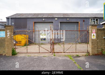 Rostig verschlossene Tore am Eingang zu einem schäbigen Gelände auf einem Industriegebiet Stockfoto