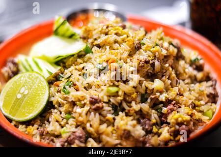 Nahaufnahme von gebratenem Reis aus thailändischem Rindfleisch mit halbgrüner Zitrone und Sauce auf der Seite Stockfoto