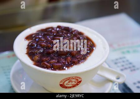 Hongkong, August 2018. Berühmter Milchpudding aus roten Bohnen mit Doppelhaut in einer weißen Schüssel mit Yee Shun Milk Company Logo. Stockfoto