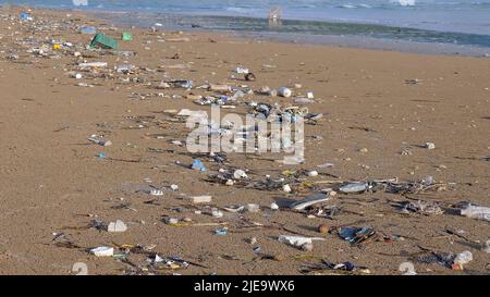 Plastikverschmutzung und eine andere Art von Müll am Meeresstrand. Verschmutzung durch Plastikmüll an der Küste. Plastikflaschen, Tüten an der Küste nicht angemessen Stockfoto