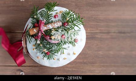 Deutscher Weihnachtskuchen auf Holztisch mit festlichen Verzierungen. Der Dresdner Stollen ist ein traditioneller deutscher Kuchen mit Rosinen. Weihnachtsgeschenk. Stockfoto