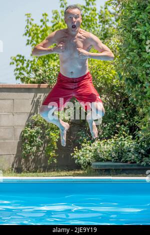 Ein Mann taucht im Gorilla-Stil in den Pool Stockfoto