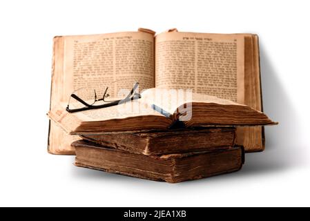 Alte abgenutzte, schäbige jüdische Bücher in Ledereinband und offene, verschwommene Tora im Hintergrund. Nahaufnahme. Selektiver Fokus Stockfoto