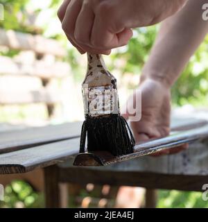 Der Maler malt die hölzernen Möbelelemente, lackieren das Holz mit dem Pinsel. Stockfoto