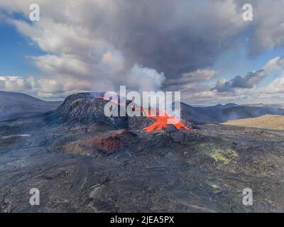 Vulkankrater in Island während des Tages. Ausbruch auf der Halbinsel Reykjanes. Rotes Magma und Lava fließen aus dem Vulkan. Wolken und Dampf am Himmel Stockfoto