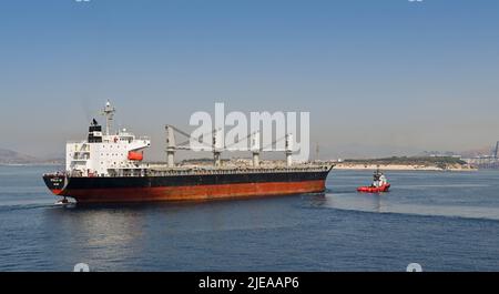 Piräus, Athen, Griechenland - 2022. Juni: Das große Frachtschiff Stella GS wird mit einem Schlepper in den Hafen von Piräus geführt. Stockfoto