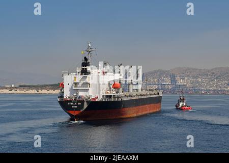 Piräus, Athen, Griechenland - 2022. Juni: Das große Frachtschiff Stella GS wird mit einem Schlepper in den Hafen von Piräus geführt. Stockfoto