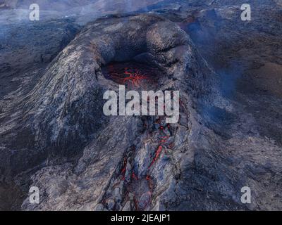 Vulkankrater von oben. Blick auf die Strukturen der roten Lava im Krater-Maul. Vulkan kurz vor Ausbruch. Dunkler, abgekühlter Magmagestein Stockfoto