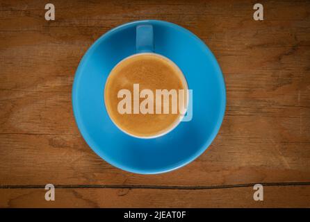 Frischer Robusta-Kaffee in blauer Tasse auf schmutzigem alten Holztisch von oben Stockfoto