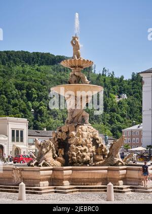 Nahaufnahme des barocken Residenzbrunnens in Salzburg, Österreich, mit Skulpturen und historischer Stadtarchitektur. Stockfoto