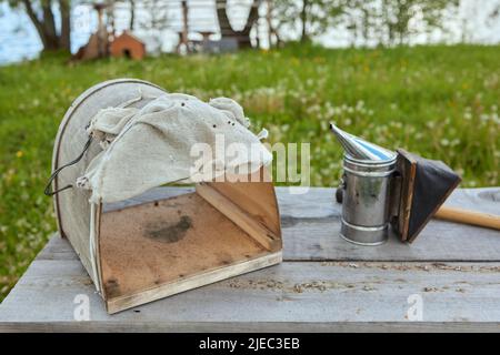 Bienenraucher auf der Oberseite eines Bienenstocks an einem Sommermorgen rauchen. Eine Grundausstattung der Imkerei. Bienenzuchtkonzept Stockfoto