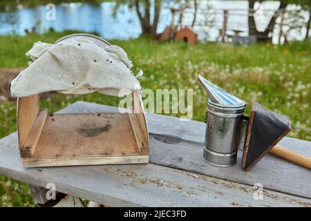 Bienenraucher auf der Oberseite eines Bienenstocks an einem Sommermorgen rauchen. Eine Grundausstattung der Imkerei. Bienenzuchtkonzept Stockfoto