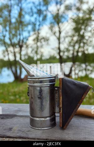 Bienenraucher auf der Oberseite eines Bienenstocks an einem Sommermorgen rauchen. Eine Grundausstattung der Imkerei. Bienenzuchtkonzept Stockfoto